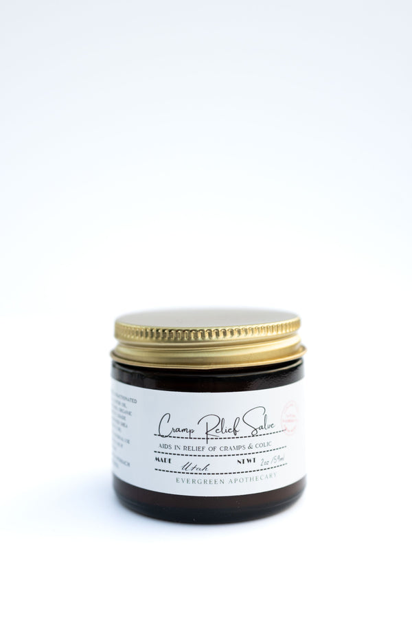 Evergreen Apothecary Menstrual Cramp Salve in a small jar, natural herbal remedy for menstrual pain relief.