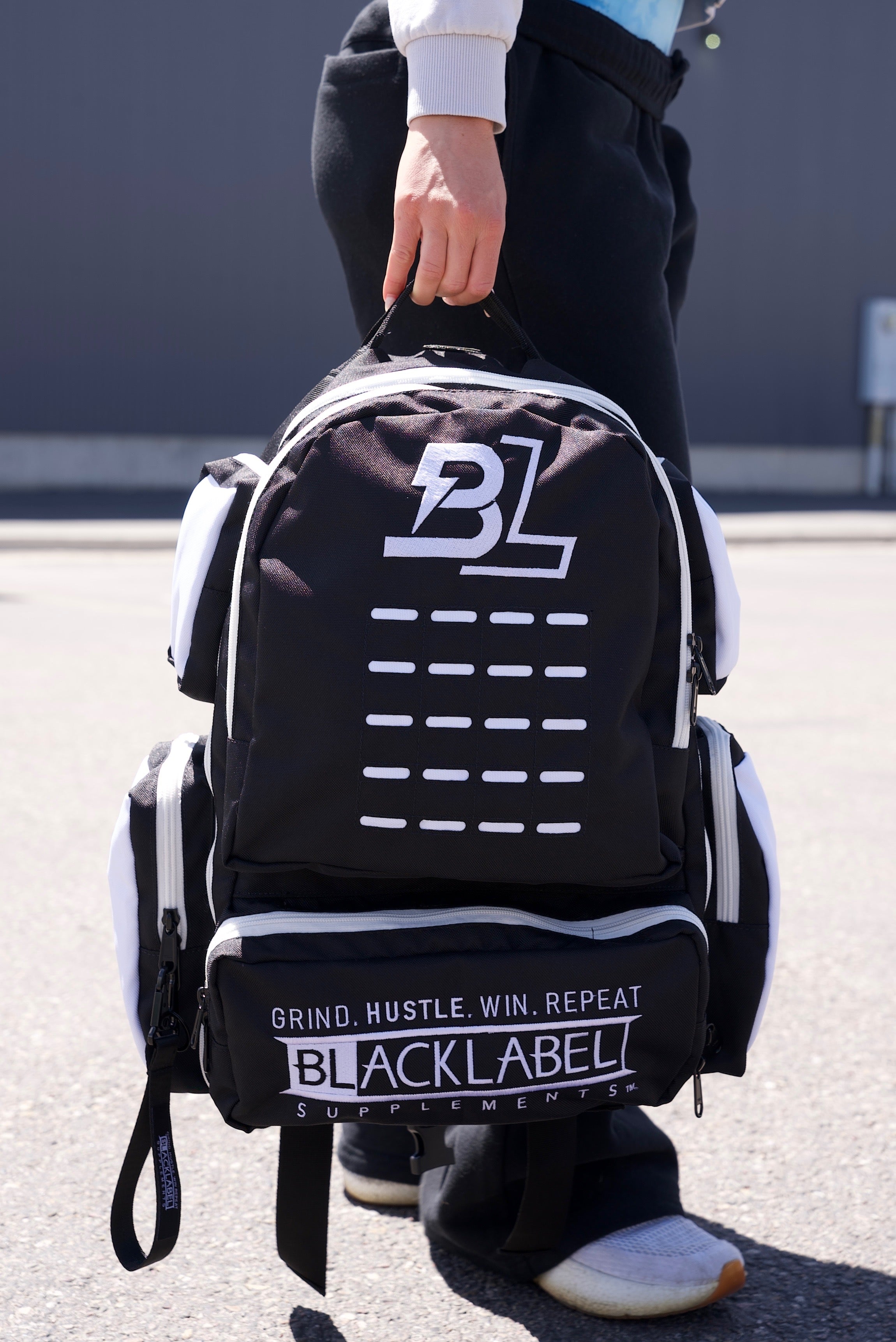 BlackLabel 26L backpack from BLACKLABEL Supplements, showing a sleek black backpack with multiple compartments and adjustable straps.