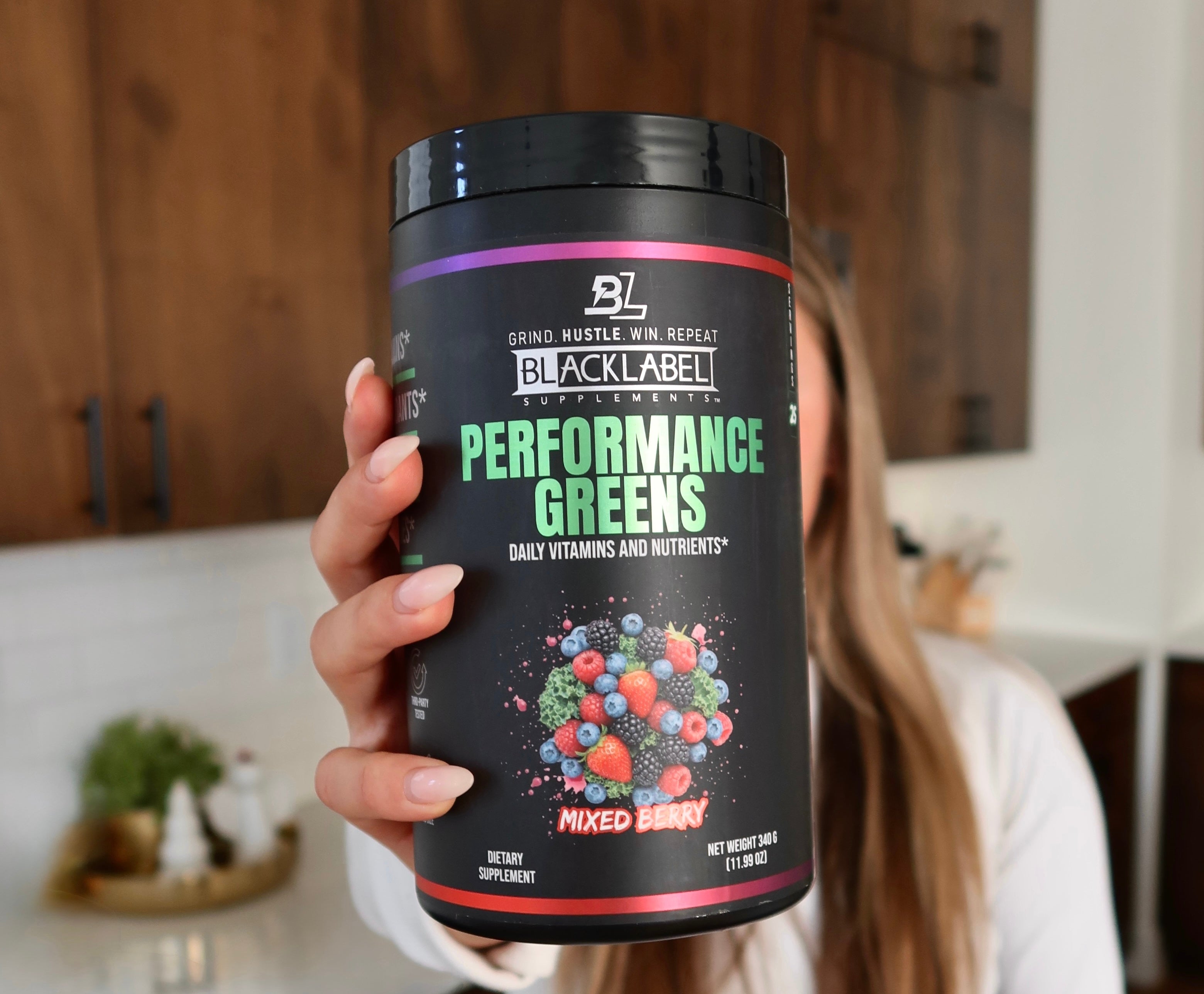 Blacklabel Supplements Performance Greens powder in a green container with scoops and ingredients on the label.
