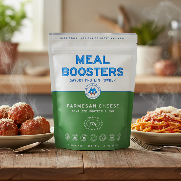 Meal Boosters Parmesan cheese collagen protein powder blend in a scoop next to meatballs and spaghetti on a plate.