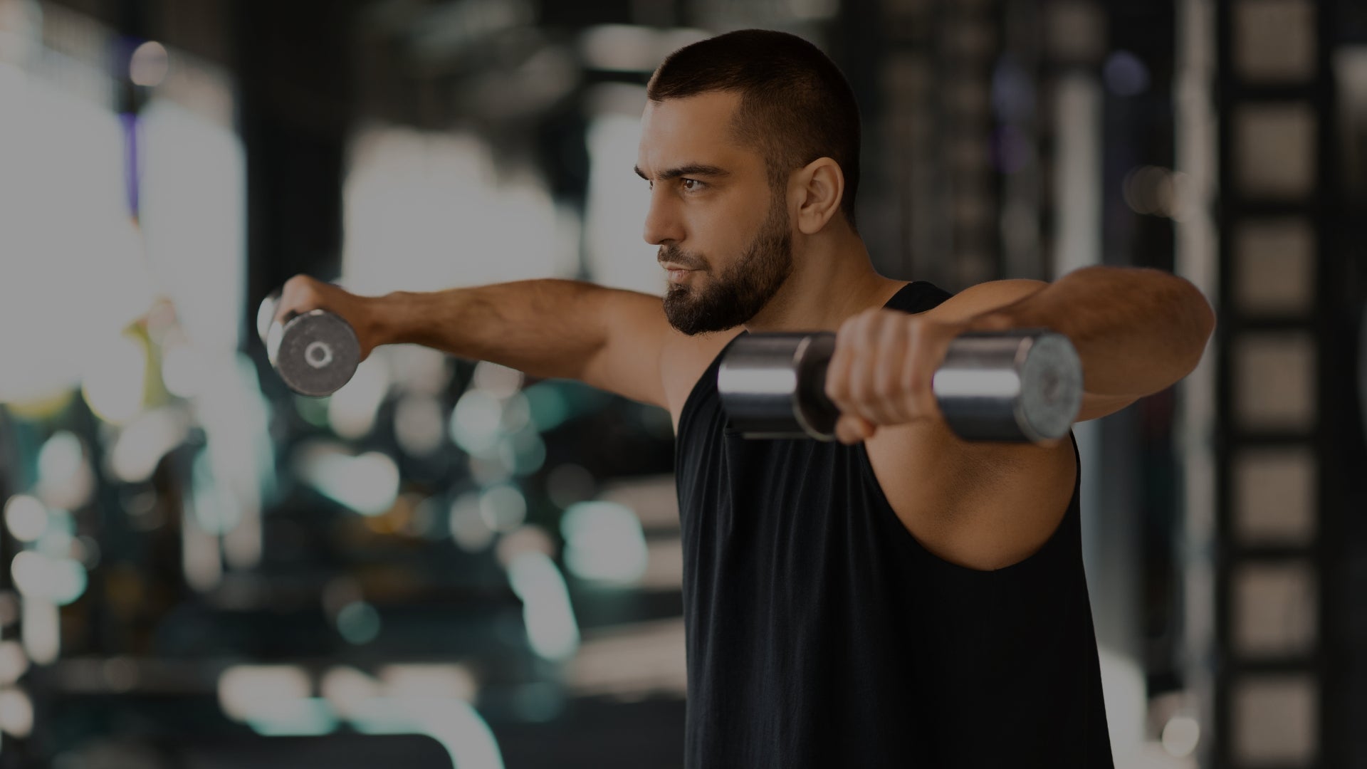 Man exercising with dumbbells in a gym setting