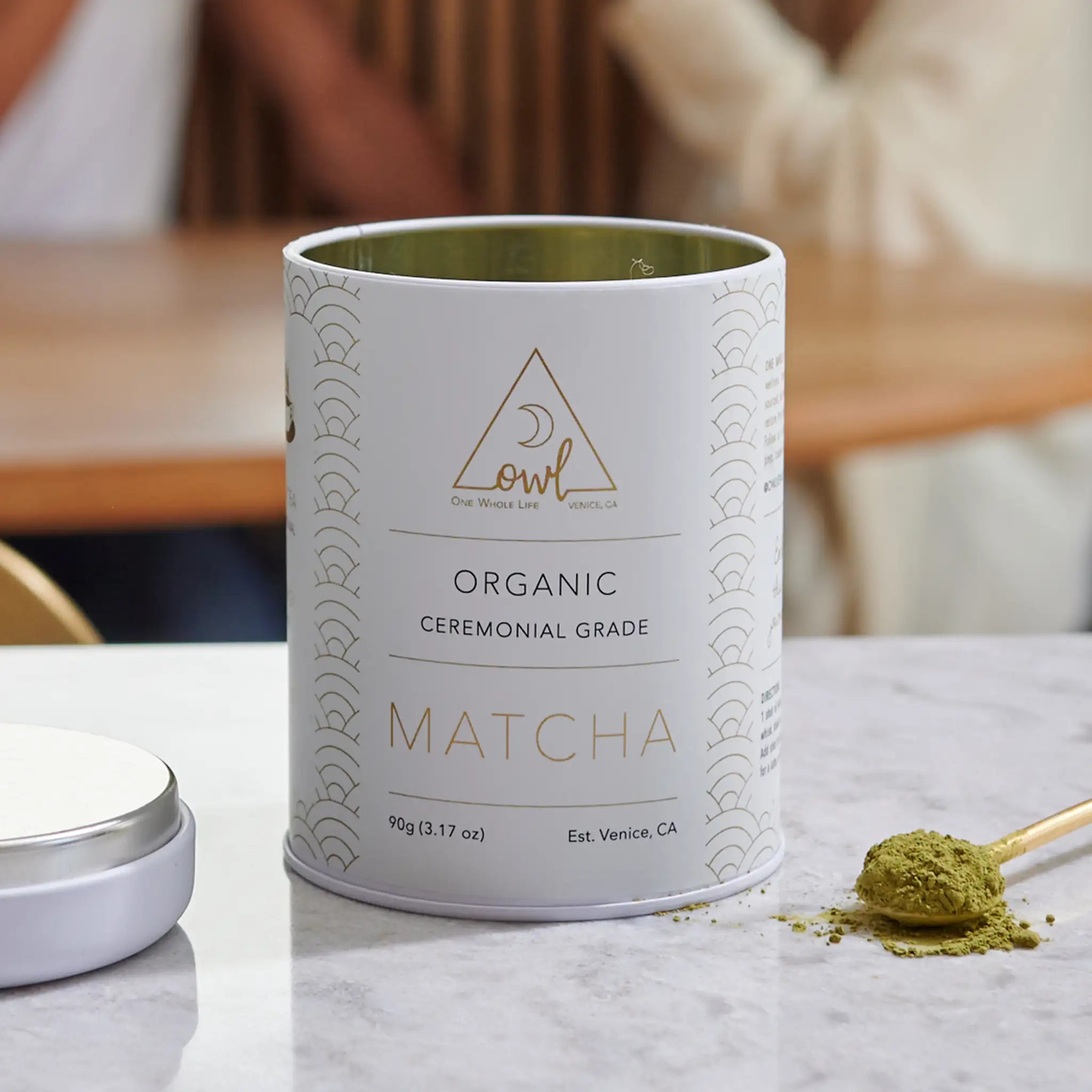 Organic Matcha Powder by OWL Venice in a green container, finely ground bright green matcha tea powder on a white background.