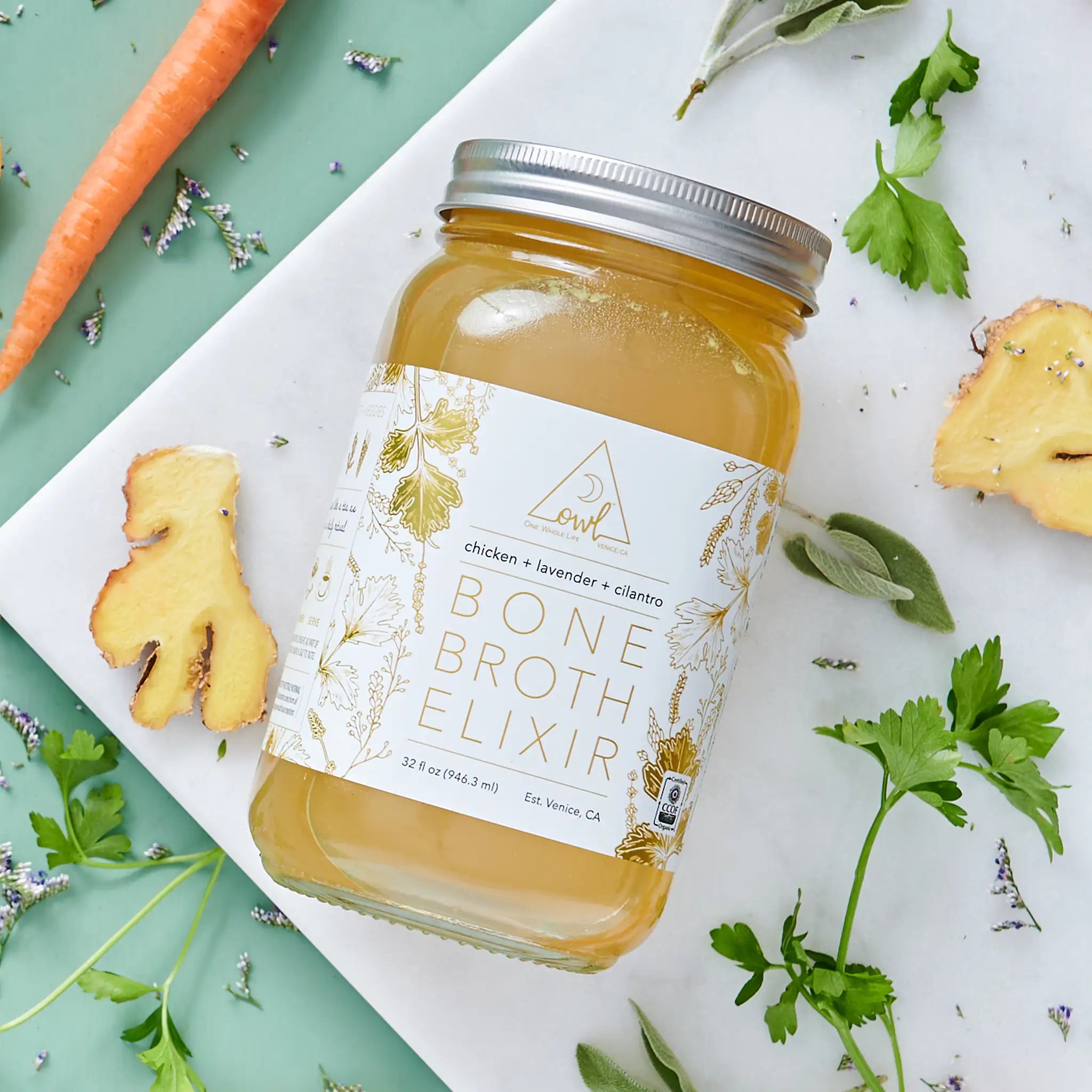 Organic chicken bone broth elixir in a glass bottle, showcasing the OWL Venice brand label and natural, nourishing liquid inside.