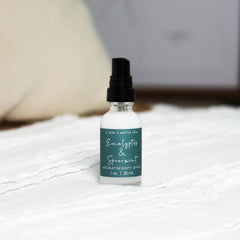Eucalyptus and spearmint aromatherapy spray by A Girl's Gotta Spa! in a clear glass spray bottle with a white cap.