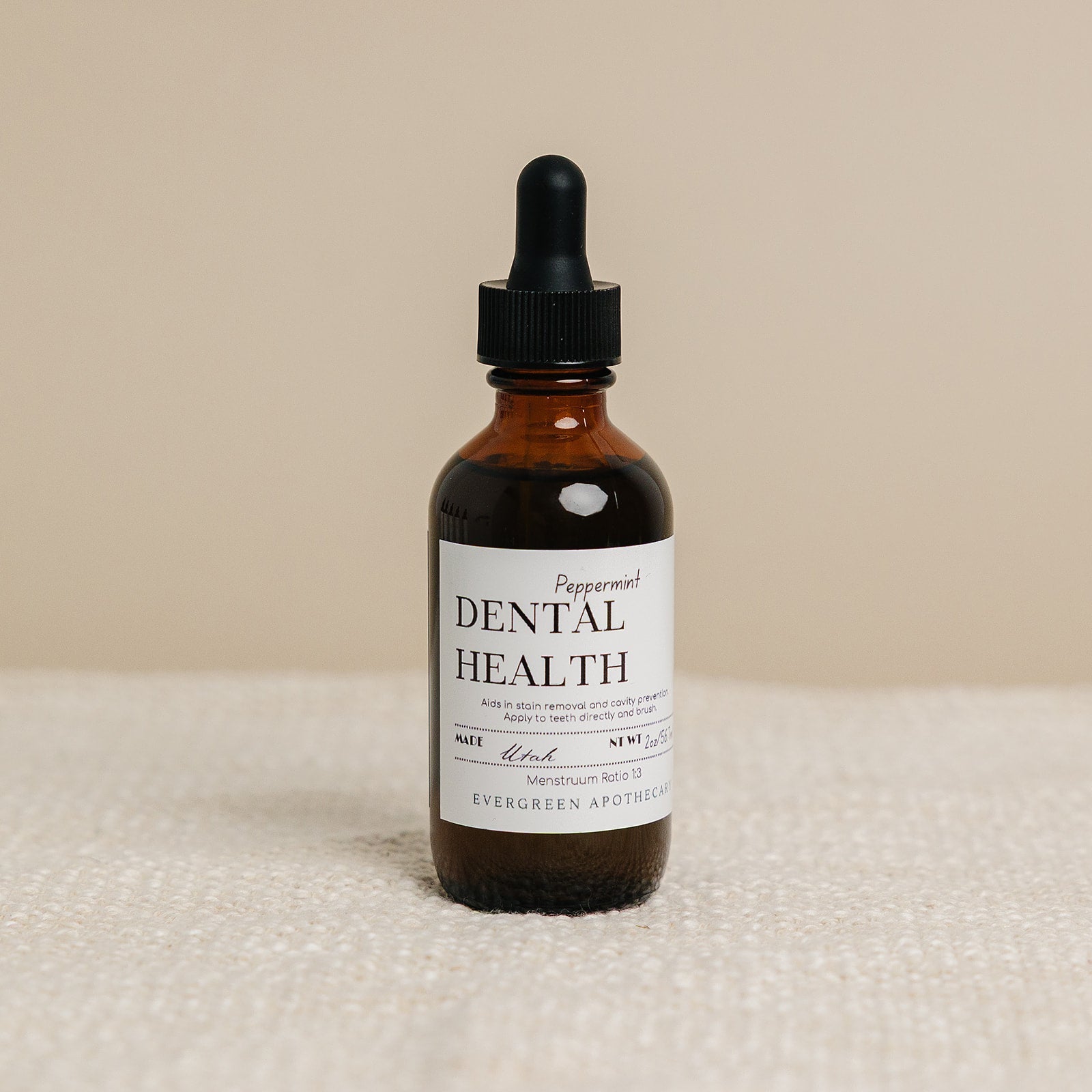 Evergreen Apothecary Dental Health oil brushing supplement with peppermint flavor, featuring a dropper bottle and fresh mint leaves.