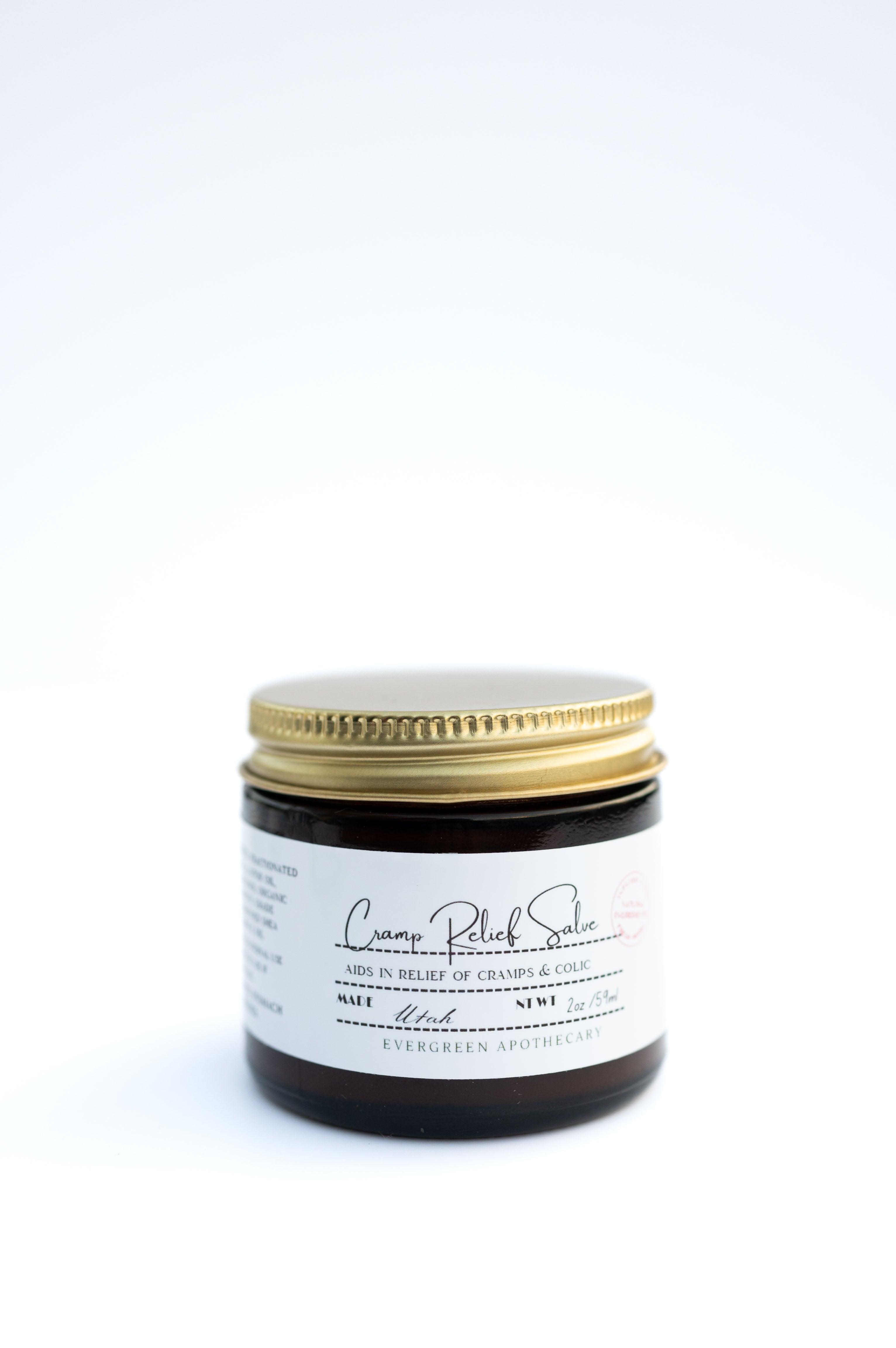 Evergreen Apothecary Menstrual Cramp Salve in a small jar, natural herbal remedy for menstrual pain relief.