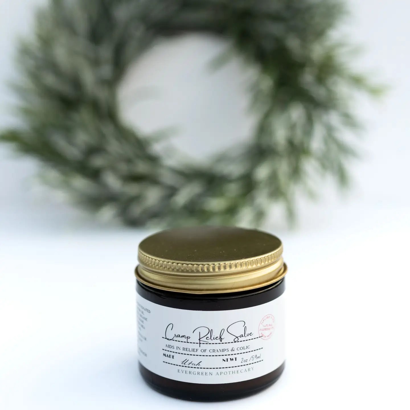 Evergreen Apothecary menstrual cramp salve in a small jar, designed to soothe menstrual discomfort with natural ingredients.
