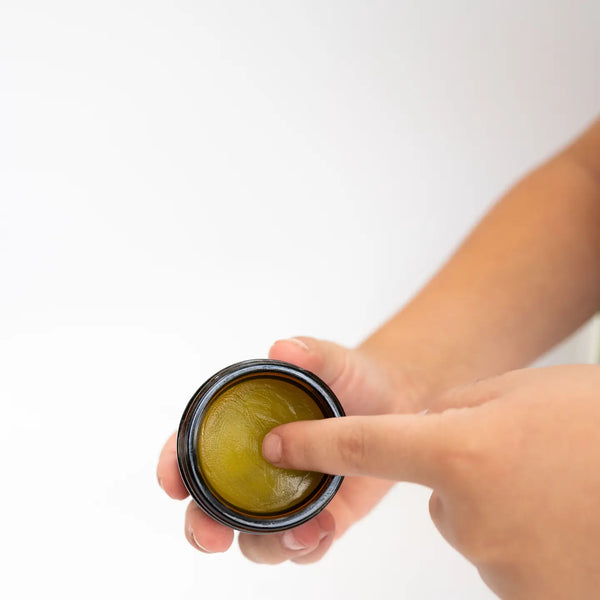 Evergreen Apothecary menstrual cramp salve in a small jar, with herbal ingredients visible, designed to soothe menstrual discomfort.
