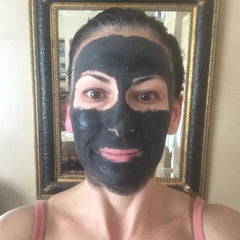 Glimmer Goddess Organic Dead Sea Mud Mask for exfoliating and rejuvenating skin, in a 2 oz jar with a natural clay texture.